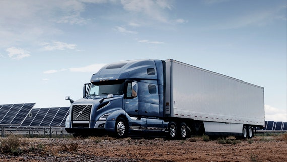 A Volvo truck driving on a scenic road.